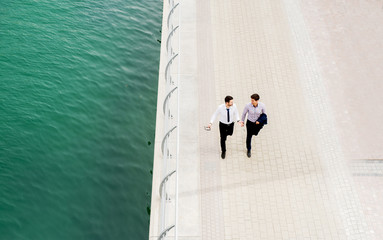 Top view of two stylish businessmen walking near the river.