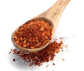 pile crushed red cayenne pepper, dried chili flakes, seeds and wooden spoon isolated on white background