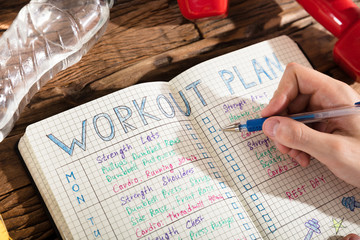 Person Making Note Of Workout Plan On Notebook
