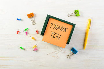 Thank you written on post note sticker with pen on light wooden table, top view. Concept of appreciate, business, information and gratitude
