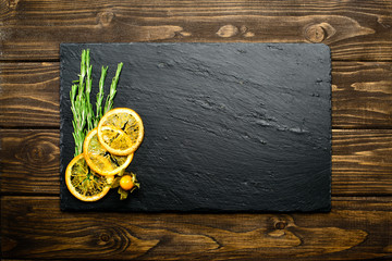 Fototapeta na wymiar sliced lemon and herbs on dark wooden background with copyspace for text, top view