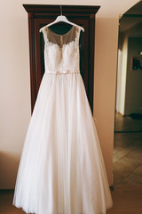 Fototapeta na wymiar A beautiful wedding dress hanging in a room