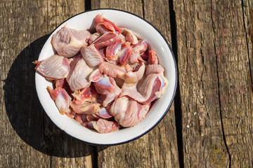 Raw chicken gizzards in metal enamelled bowl on rustic wooden table