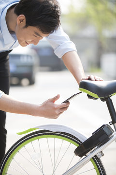 Young man scanning a QR code to unlock a share bike