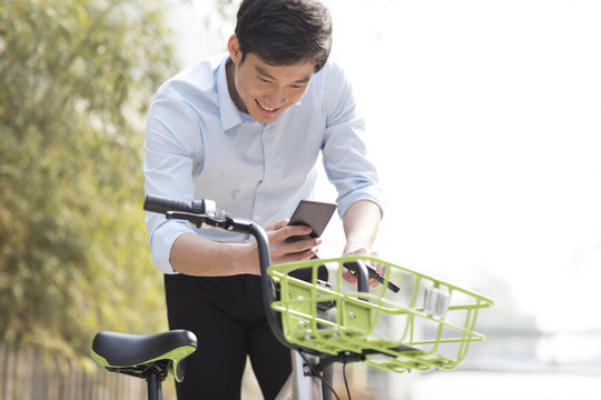 Young man scanning a QR code to unlock a share bike