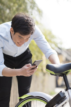 Young man scanning a QR code to unlock a share bike