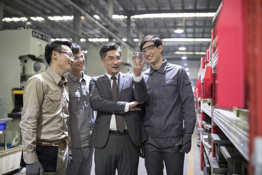 Businessman and engineers checking machine parts in the factory