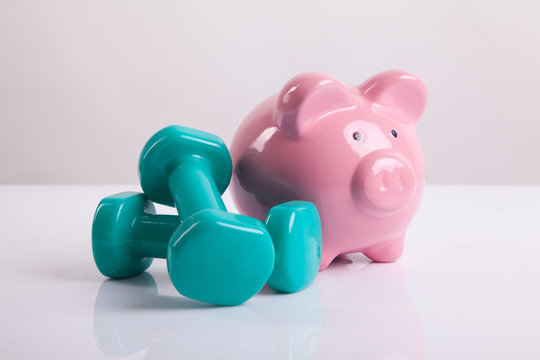 Green dumbbells with piggy bank for health insurance concept