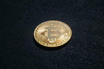 Golden coin of Bitcoin on black