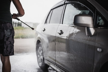 Man washing his car under high pressure water 