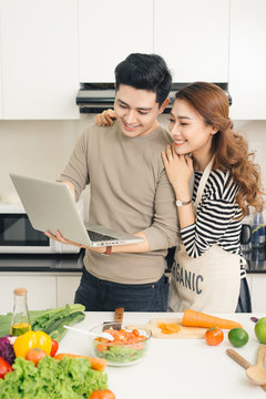 Young couple using laptop to look up recipe for their meal