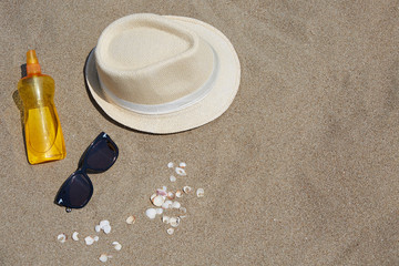 Hat, sunglasses, sunbathing oil on the beach.