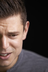 Obraz premium Close up of crying young white man looking down, vertical