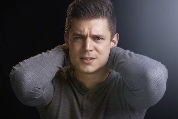 Portrait of angry young white man with hands behind his neck