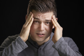 Portrait of a worried young white man holding head