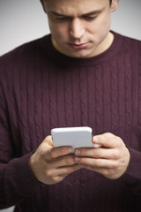 Vertical portrait of a young white man using a smartphone