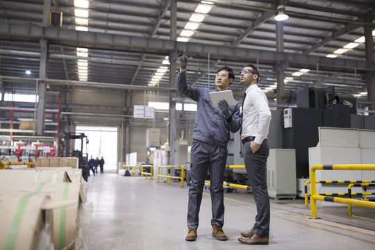Businessman and engineer talking in the factory