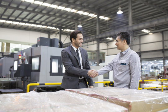 Businessman shaking hands with engineer in the factory