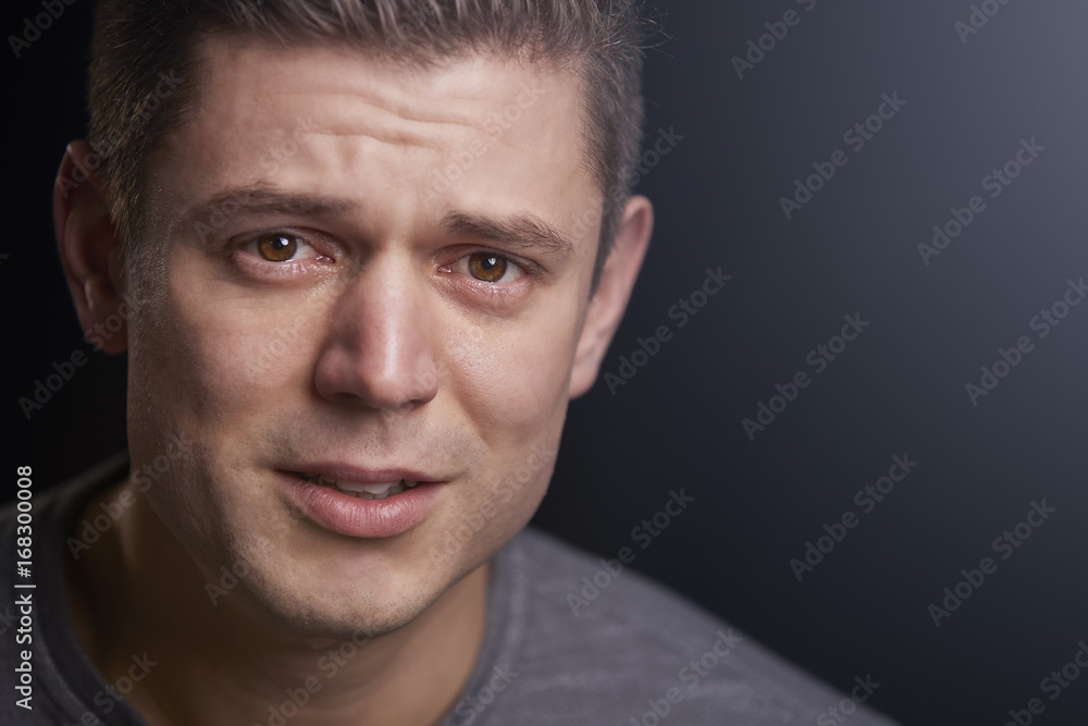 Wall mural Close up portrait of upset young white man looking to camera