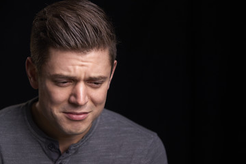 Portrait of crying young white man looking down