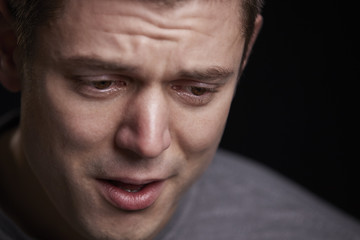 Close up portrait of crying young white man looking down