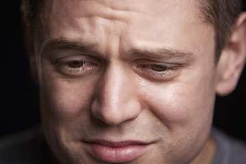 Close up portrait of crying young white man looking down