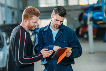 Automechanic and client looking digital tablet