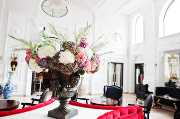 Close-up photo of a huge bouquet made of hydrangeas standing on the table in large luxurious room.