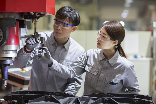 Young engineers checking machine in the factory