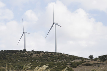 Wind turbine renewable energy source summer landscape with clear blue sky and field in the foreground