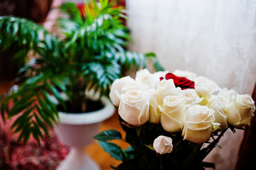 Close-up photo of a bouquet made out of white roses and one red rose.