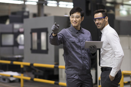 Businessman and engineer talking in the factory