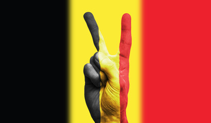 Fototapeta premium belgium national flag painted onto a male hand showing a victory, peace, strength sign