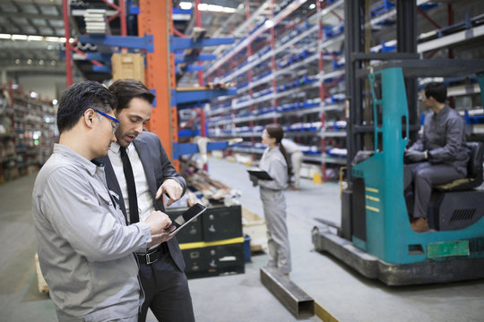 Businessman and engineer talking in the factory