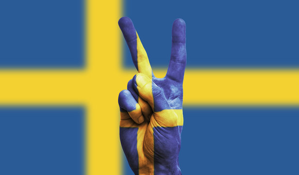 Sweden national flag painted onto a male hand showing a victory, peace, strength sign