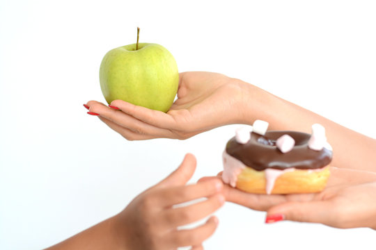 Healthy food education with little girl choosing unhealthy sweet donut instead of fresh green apple
