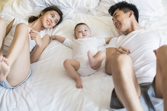 Happy young family lying on bed
