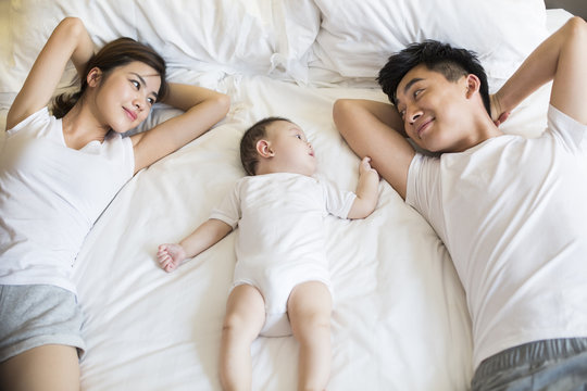 Happy young family lying on bed