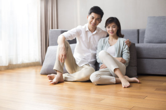 Happy young couple sitting on wooden floor