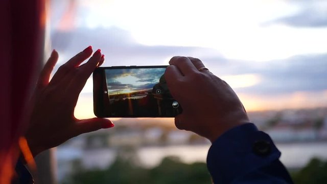 Make a photo on the phone of a beautiful sunset in the city near the river, close-up. slow motion, 1920x1080, full hd