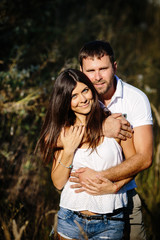 Portrait of man embracing her woman from behind on nature background