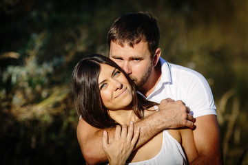 Portrait of man embracing her woman from behind on nature background