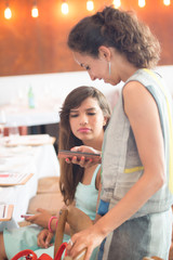 Two girls friends talking at mobile phone in cafe