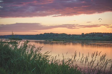 Summer sunset on the Oka river, with a flying paraglider