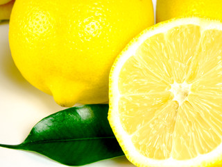 Yellow lemon with fresh green leaves over white background
