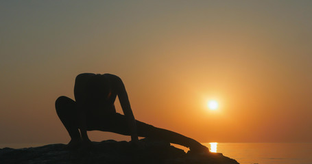 Fototapeta na wymiar Girl practices yoga near the ocean