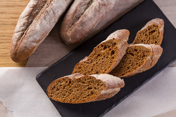French homemade baguette bread. Rye baguette on black shale.