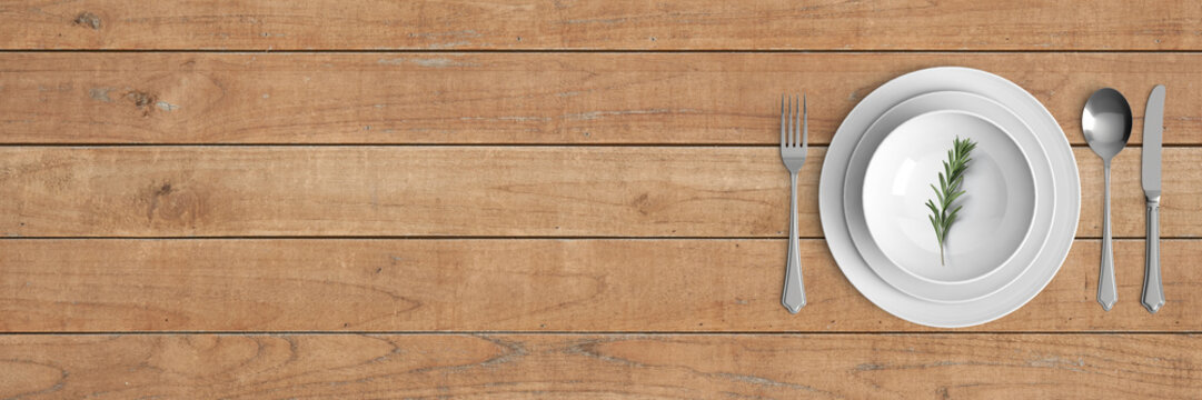 place setting with plate, bowl, knife, fork and spoon on wooden table