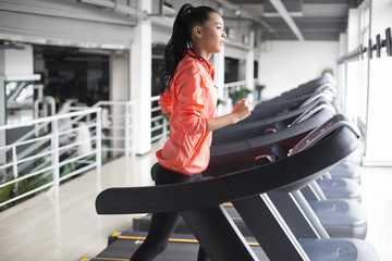 Young woman running on treadmill in gym