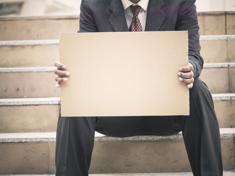 Businessman sitting on stair outdoor holding a blank pepar card board